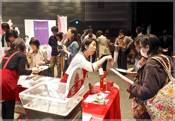 来場者と石榴の滴の説明をするスタッフ